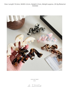 Detailed view of wave-shaped acetate hair claws in various elegant marble patterns