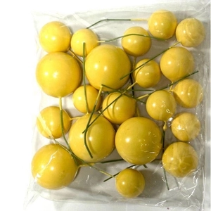 Detailed view of yellow foam berry cake toppers with green wire stems in packaging