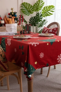 Detail of red Christmas tablecloth with snowflake and green tree patterns in a festive setting