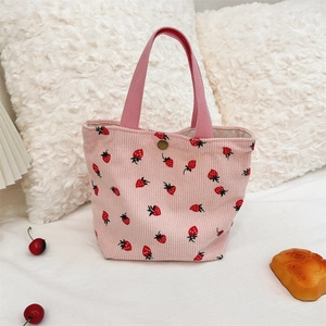 Vue détaillée de la texture du velours côtelé et des motifs fraises de ce sac rose