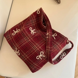 Gros plan détaillé du tissu à carreaux rouges avec broderie nœud blanc sur le sac