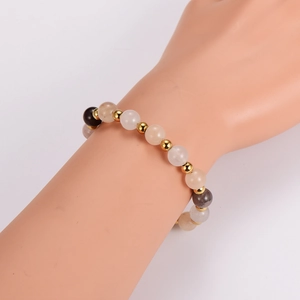 Agate beaded bracelet with pink and brown stones and gold metal spacers on model's wrist