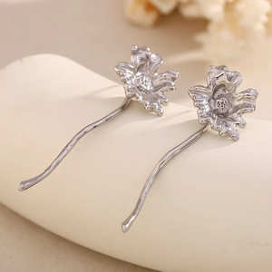 Macro detail of silver floral stud earrings with 316L stainless steel texture and hook
