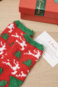 Detail of coral fleece Christmas socks with reindeer and tree patterns on a wooden desk