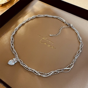 Detailed macro view of multi-layered silver necklace with zircon heart pendant and lobster clasp