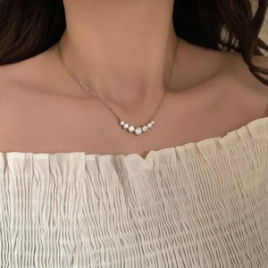 Silver smile necklace with seven zircon stones worn by a model on white clothes