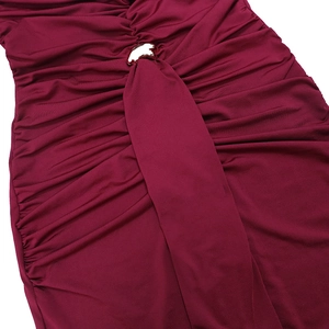 Macro shot of ruched burgundy dress fabric with a central metallic arc buckle detail