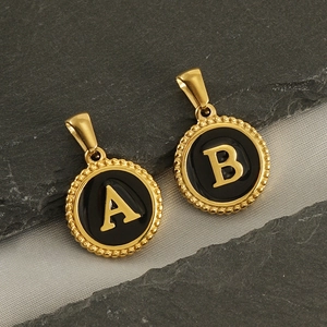 Close-up of 18K gold-plated circular pendants with black enamel and letters A and B