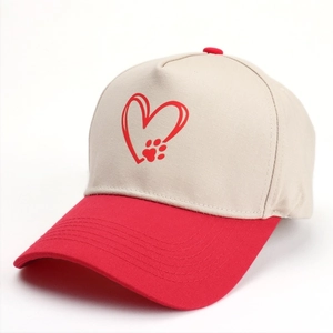 Gros plan du motif cœur et patte sur la casquette de baseball beige et rouge
