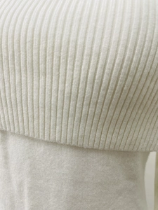 Close-up of elegant off-shoulder knit dress showing vertical ribbing and smooth knit texture