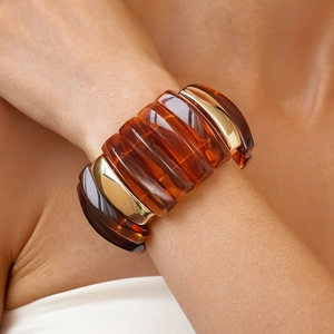 Detail of amber acrylic segments with golden metal links on a wide geometric bracelet