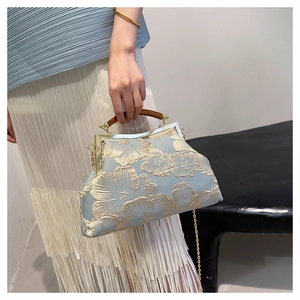 Detailed embroidery on light blue satin handbag with gold floral patterns and wooden handle