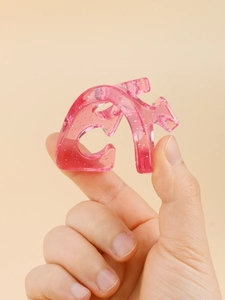 Close-up of a pink translucent resin hair claw clip with silver glitter particles