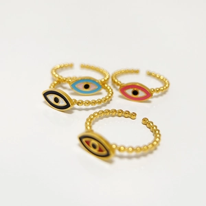 Detail of four gold evil eye rings with colorful enamel finishes and beaded band design