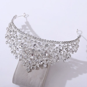 Macro detail of silver bridal crown with floral rhinestone patterns on velvet stand