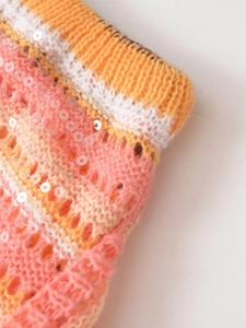 Makroansicht des Strickgewebes mit rosa-orangefarbenen Streifen und Pailletten