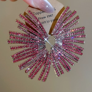 Macro detail of large rose pink rhinestone fan-shaped earrings with radial design