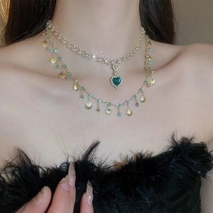 Detail view of gold layered necklace with blue heart pendant and shell accents