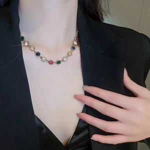 Close-up of luxury gold bracelet featuring colorful round cut gemstones on black blazer