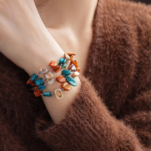Detail of layered multi-strand bracelet with irregular colorful shell beads and woven cord