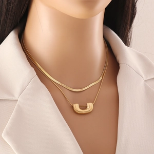 Double layered gold necklace featuring a sleek snake chain and U-shaped pendant