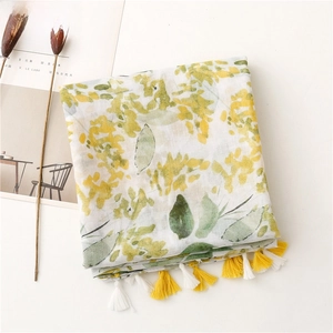 Detailed view of yellow floral print scarf with soft dual-color tassels on a white base