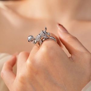 Close-up of a silver puppy ring with rhinestones worn on a finger in soft natural light
