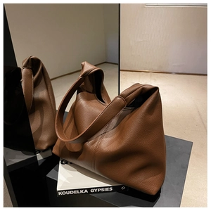 Detail view of the brown leather tote bag on a black stand with a mirror background