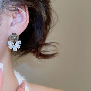 Detail of flower cluster earrings with brown round stones and teardrop zircons on ear