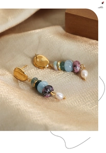 Detail of bohemian drop earring with colorful natural stones and a baroque pearl on satin