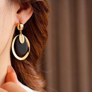 Close-up of gold-plated resin oval earring with Hand Made engraving on model
