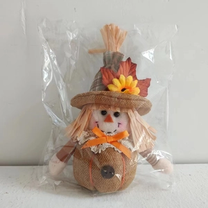Detail of harvest scarecrow doll with pumpkin body and sunflower hat in packaging
