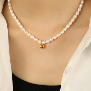 Elegant freshwater pearl necklace with gold ball pendant worn on a female model