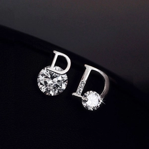 Detailed macro view of asymmetric D-shaped silver earrings with sparkling zircon stones