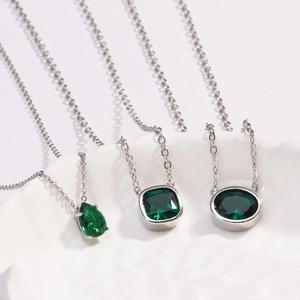 Close-up of emerald green pendants in pear, cushion and oval cuts on silver chains