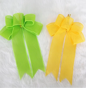 Close-up of yellow and green faux linen Easter bows with long ribbons on soft plush fabric