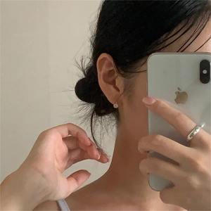 Close-up of minimalist cat eye stud earring and silver ring worn by a model