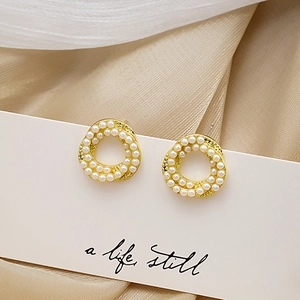 Detailed view of pearl-studded gold hoop earrings on a decorative display card