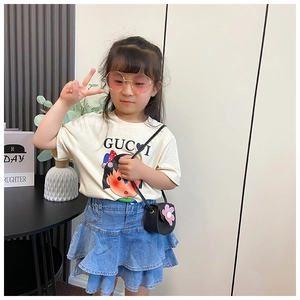 Close-up of a girl wearing an off-white cartoon t-shirt with a ruffled denim skirt