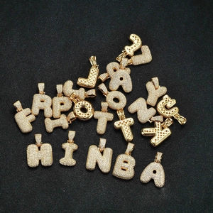 Flat lay of multiple gold-plated alphabet pendants with sparkling zircon micro-paving