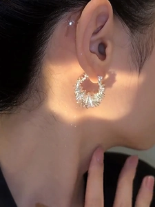 Detail of silver hoop earrings with rectangular crystals worn on a model's ear