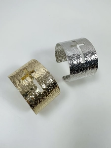 Close-up of hammered metal texture and hollow cross design on gold and silver bangles