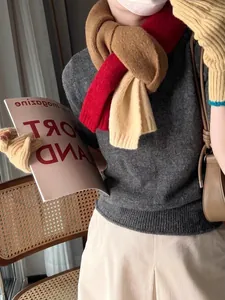 Détail d'une écharpe en maille color-block avec gants jaunes et pull gris chaud