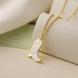 Detail view of gold chain necklace with a white enamel cowboy boot pendant and star motif