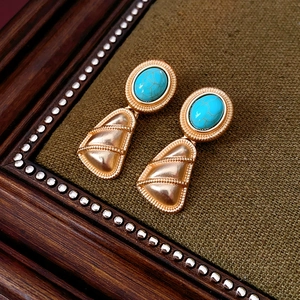 Vue détaillée de boucles d'oreilles vintage dorées avec turquoise et triangles gravés