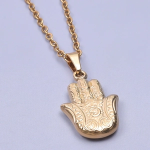 Gros plan détaillé d'un pendentif Hamsa doré aux motifs tourbillonnants avec chaîne en O
