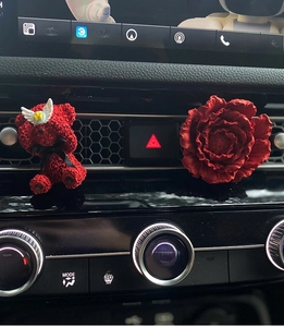 Red bear car vent clip and simulation flower diffuser mounted on automobile dashboard