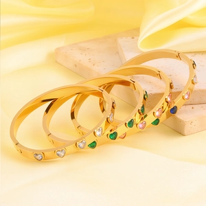 Bracelet élégant en acier titane doré avec zircons cœurs colorés sur marbre et satin