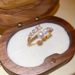 Macro detail of gold-plated twisted ring band with white pearls and sparkling zircons
