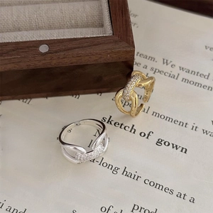 Detail of adjustable S925 sterling silver chain rings with pavé zircon stones on an open book
